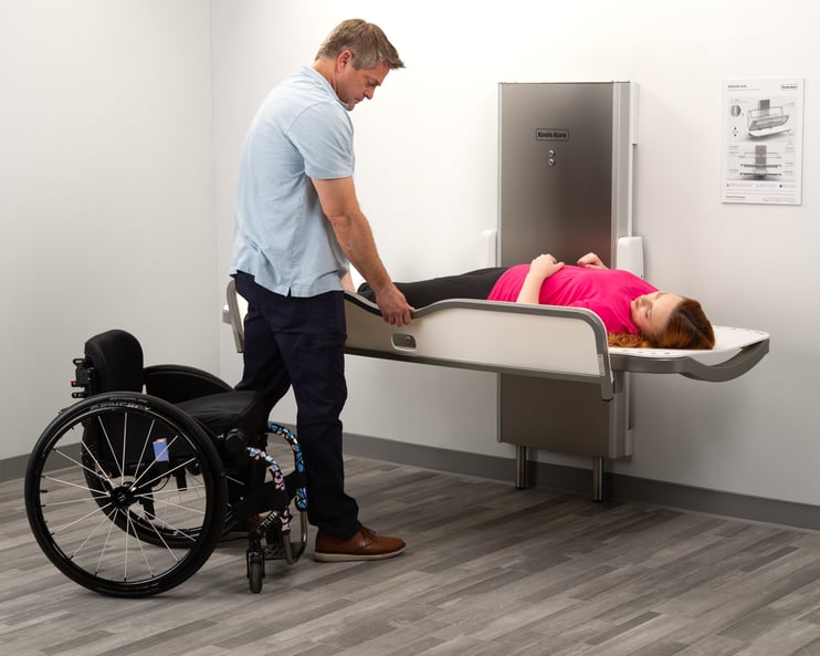 The Koala Kare KB3000-AHL Adjustable Adult Changing Station in use with a wheelchair for scale.